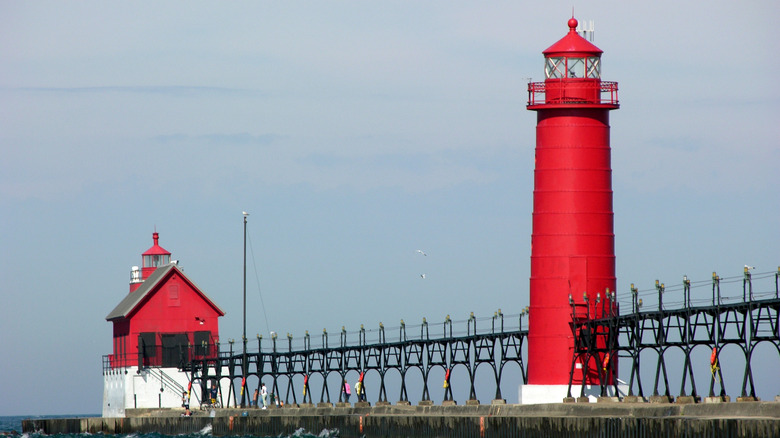 A cherry red lighthouse and fog house on the Lake Michigan shoreline in Grand Haven, Michigan.