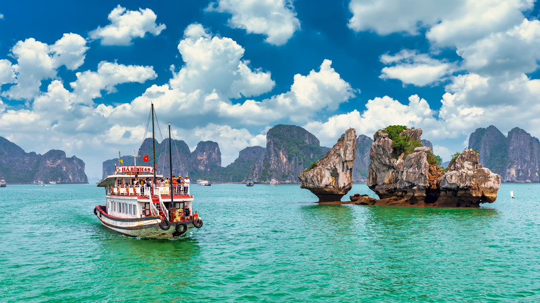 Tourist boat on green-blue water in Vietnam near interesting rock formations