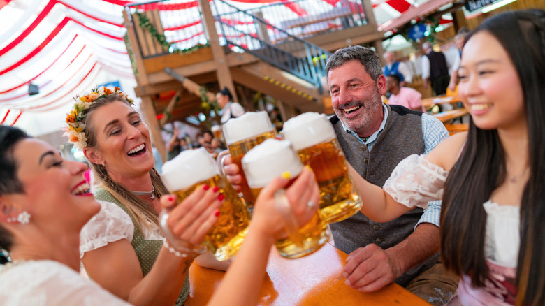 Group of friends dressed in Bavarian clothing holding large steins of German beer