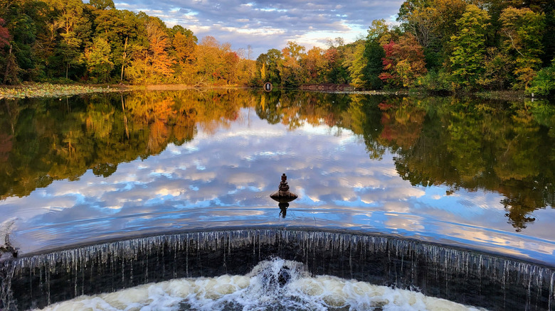 A pond and small waterfall in Forest Park in Springfield, Massachusetts, surrounded by autumnal foliage