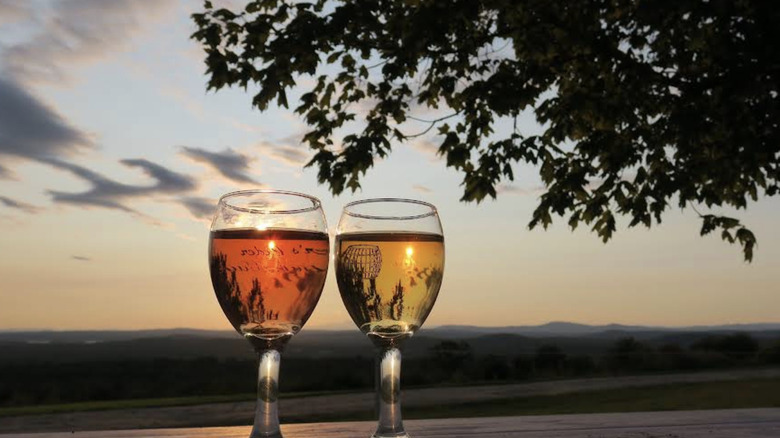 Two glasses of wine at sunset with a hilly landscape in the background