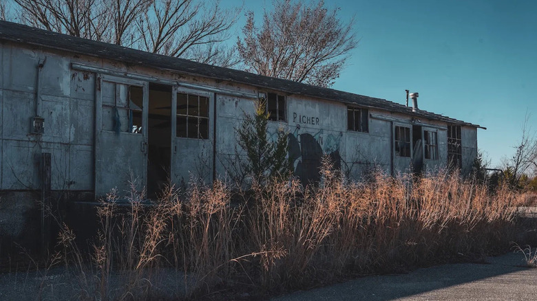 A manufactured home in a field of dead grass with two sets of double sliding doors open