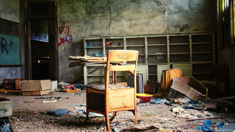 A wooden chair and desk in a destroyed classroom at the abandoned Skedee High School