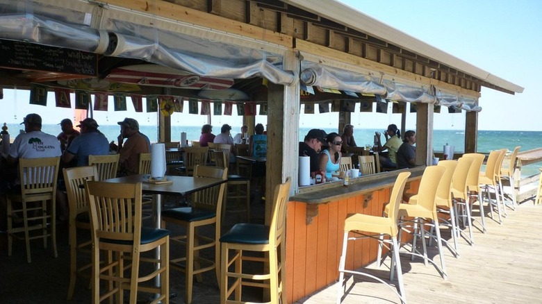 People sitting at Fish Heads Bar and Grill with the ocean in the background, South Nags Head, Outer Banks, North Carolina