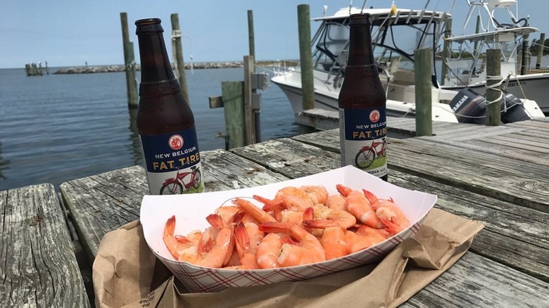 A basket of spiced shrimp and two beers, on a weathered picnic table overlooking Hatteras Village's fishing harbor on Hatteras Island in the Outer Banks
