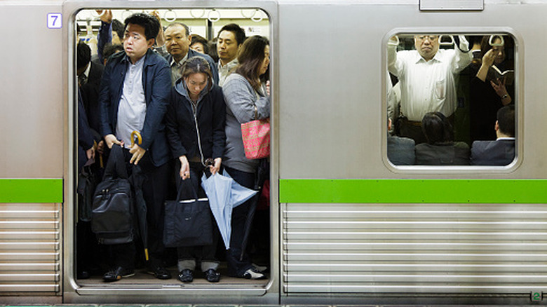 View of commuters at the Nishi-ojima station, crowded inside of a packed subway car, waiting for the doors to close