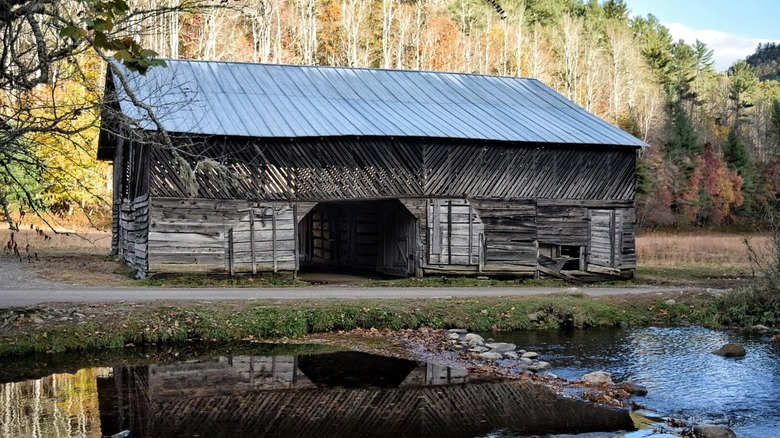 Reflection of an abandoned wooden farmhouse on water in Cataloochee North Carolina