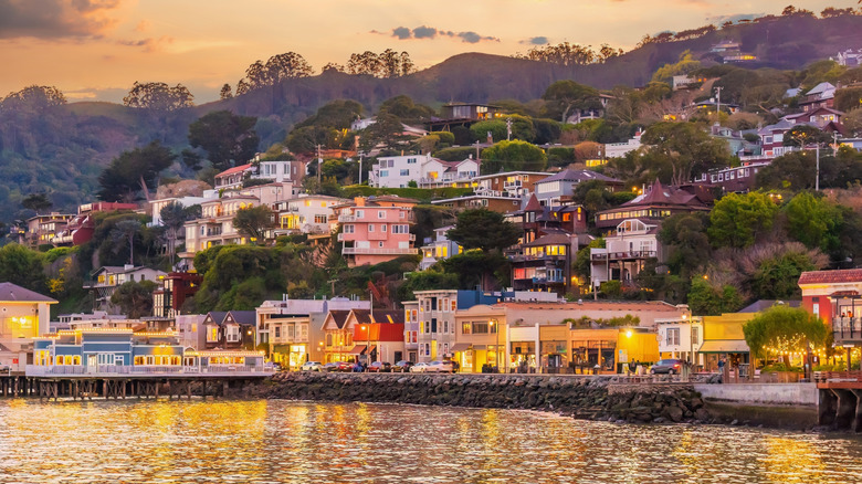 Buildings, a pier, and hills at the Sausalito waterfront at sunset.