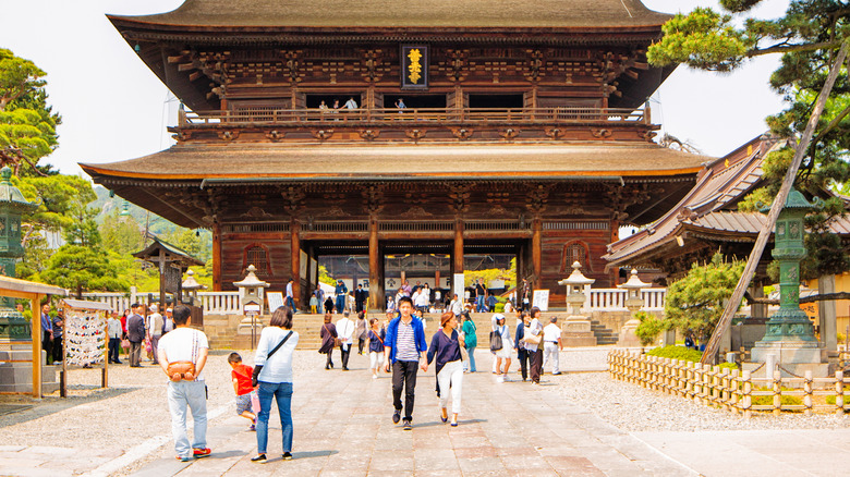 tourists walking through the gate of a towering temple