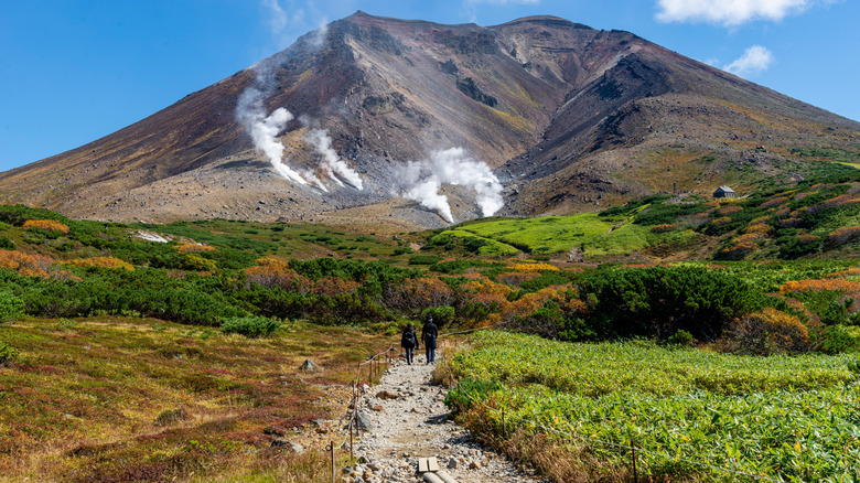 two hikers on a trail leading up the steamy mountain