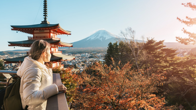 woman standing on balcony overlooking fall colored leaves