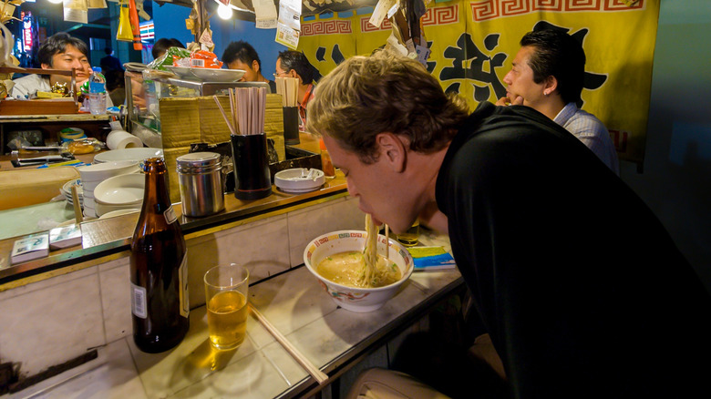 man eating noodles at food stall