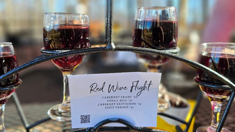 A flight of red wine with four glasses and a display card at Cave Ridge Vineyard