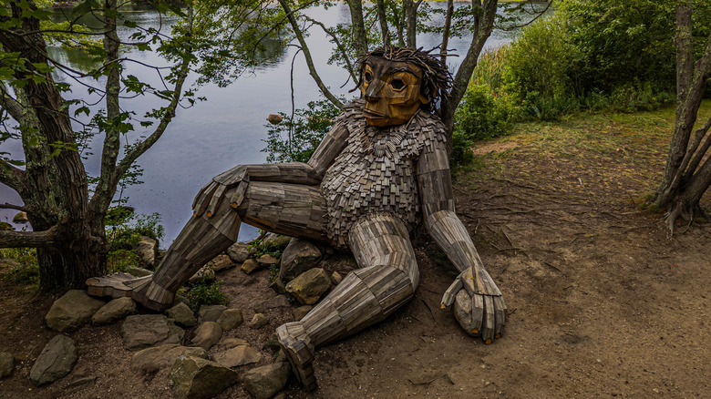 A sculpture of a troll by artist Thomas Dambo reclines near the shore of Little Nini Pond in Rhode Island