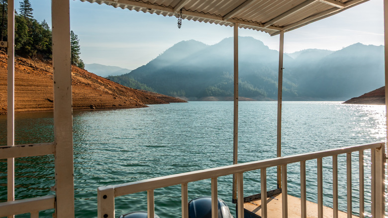 A scenic view of Shasta Lake with mountains in the distance from a boat on the water