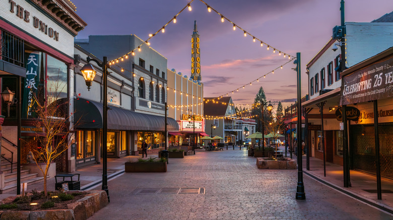 Grass Valley's shop-lined Mill Street at dusk decked with fairy lights and a tower at the background