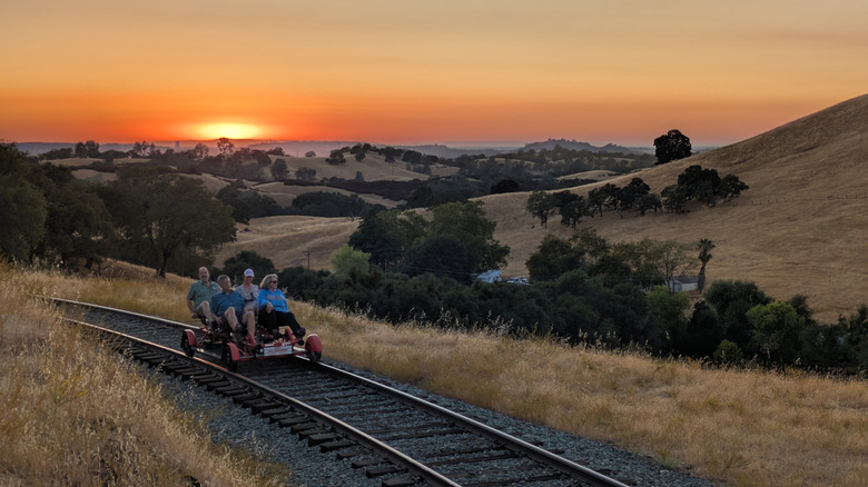 A group of four people railbiking along train tracks in Amador County, California, at sunset