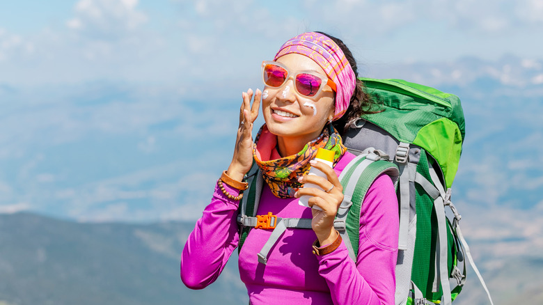 A female hiker applying suncreen