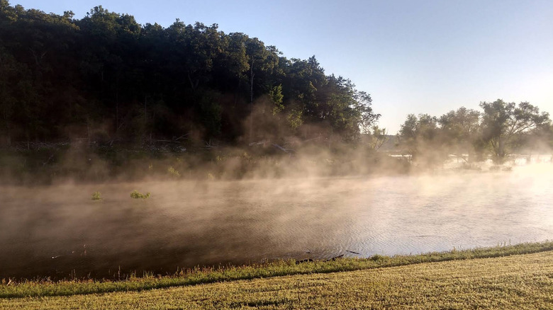 mist rising off of a lake with trees in the background at Beaver Creek Park, Missouri