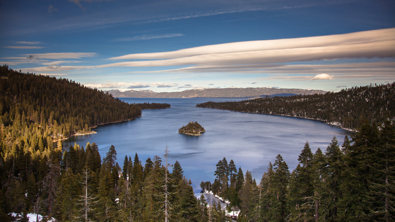 View of Emerald Bay at Lake Tahoe with pine trees and a cloud-streaked blue sky