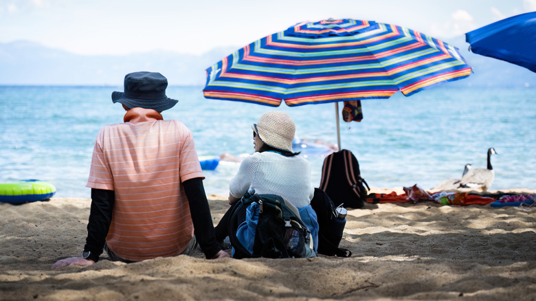 Back view of a couple sitting on a crowded Pope Beach at Lake Tahoe