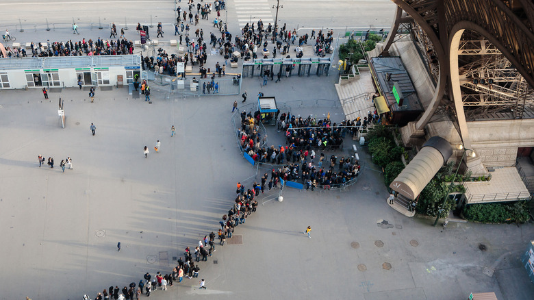 Aerial view of tourists waiting in a lengthy queue to visit the Eiffel Tower.