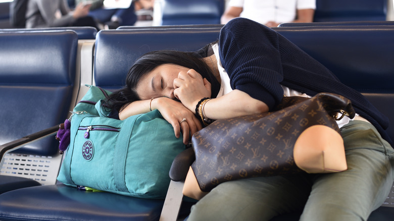 An airplane passenger waiting for a delayed flight sleeps in the terminal gate area at Denver International Airport