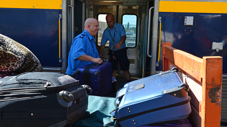 Baggage handlers load passengers' checked luggage aboard an Amtrak train in California