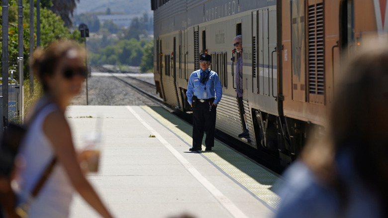 A train attendant waits as commuters board an Amtrak Pacific Surfliner train headed north at the Moorpark Train Station