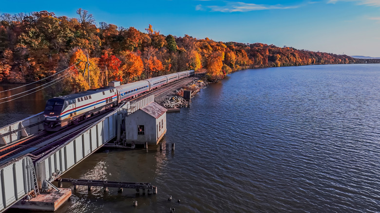 An aerial view of an Amtrak train traveling on a drawbridge track along the Hudson River in Upstate New York in the fall