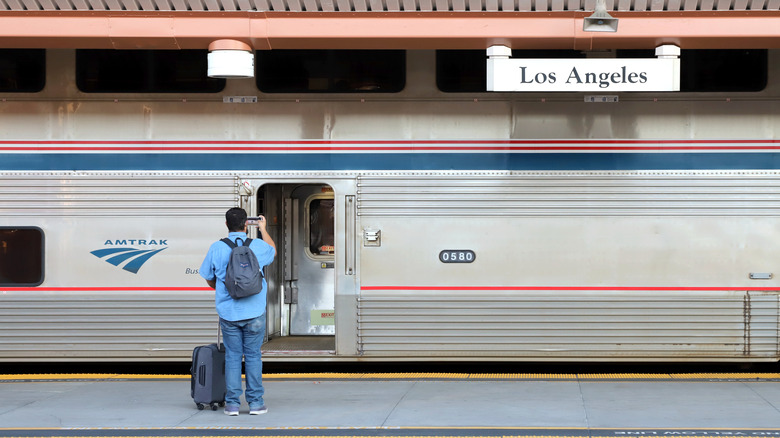 Back view of passenger with luggage taking photos before boarding an Amtrak train