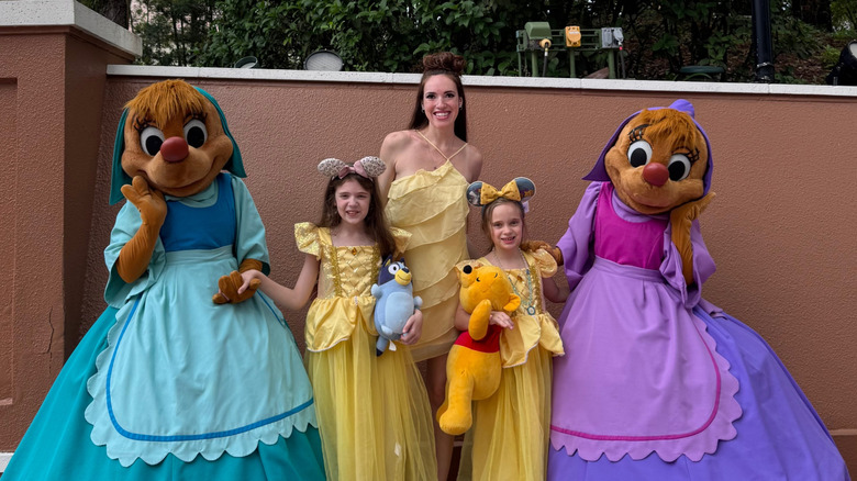 Brunette mother and daughters posing with Cinderella's female mice at Epcot