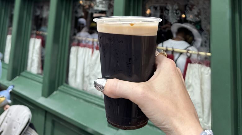 Close up of a woman's hand holding a Guinness outside of Rose & Crown pub at Epcot