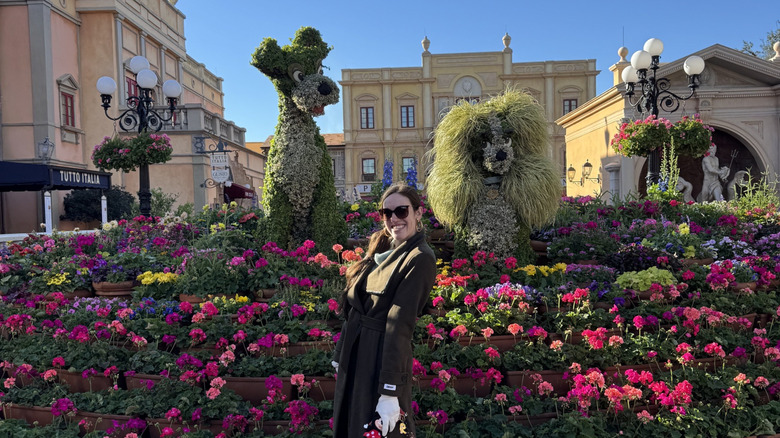 Brunette woman posing in an empty Italy pavilion with Lady and the Tramp topiaries early in the morning