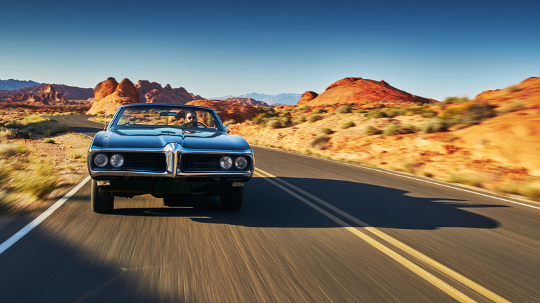 A man driving a vintage car through the desert in Nevada.