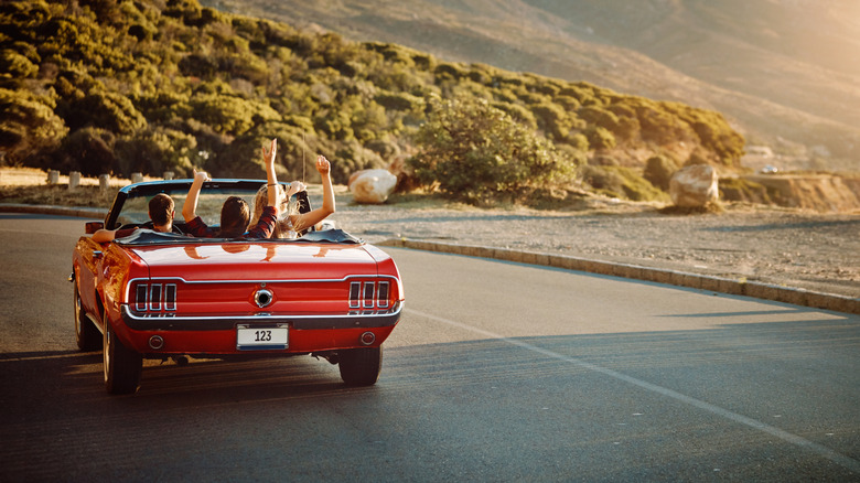 Driving away in a red convertible.
