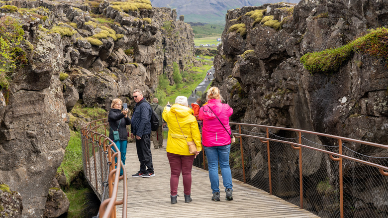 Tourists walking on a wooden ramp between rocky mountaneous walls
