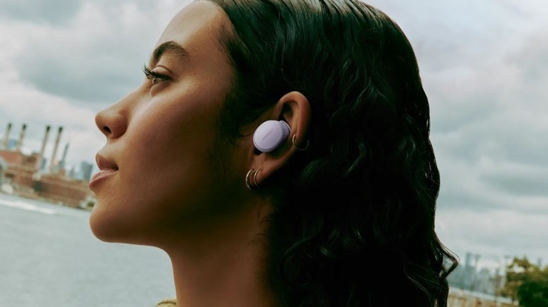 A woman wears lilac-colored Bose QuietComfort Earbuds