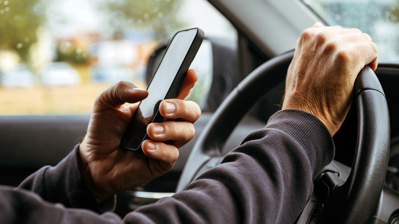 Driver checking their phone while driving a car