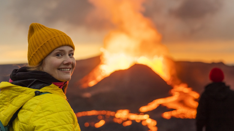 Adult female enjoying a view of a volcanic eruption wearing a hat and high visibility jacket.