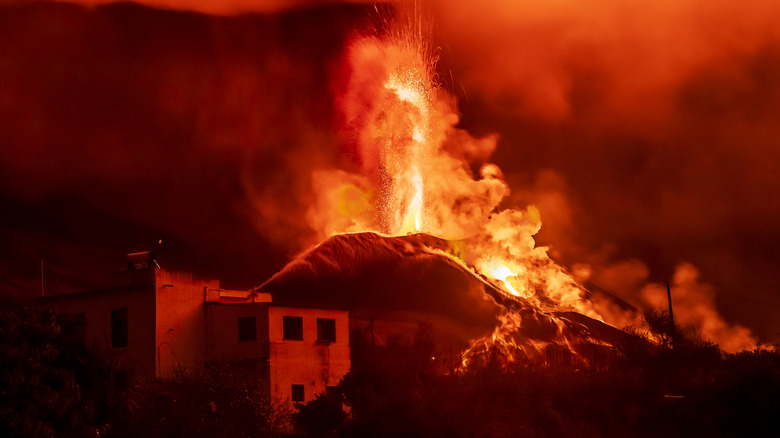 Abandoned building with an erupting volcano in the background