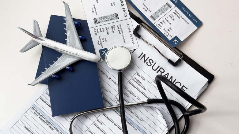Still life with airplane, stethoscope, passport, and two boarding pass portraying travel insurance.