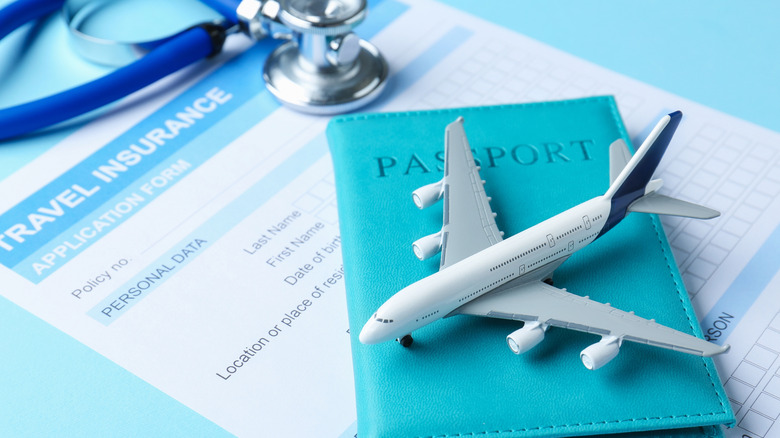 Travel insurance application form, stethoscope, passport, and plane model on light blue background
