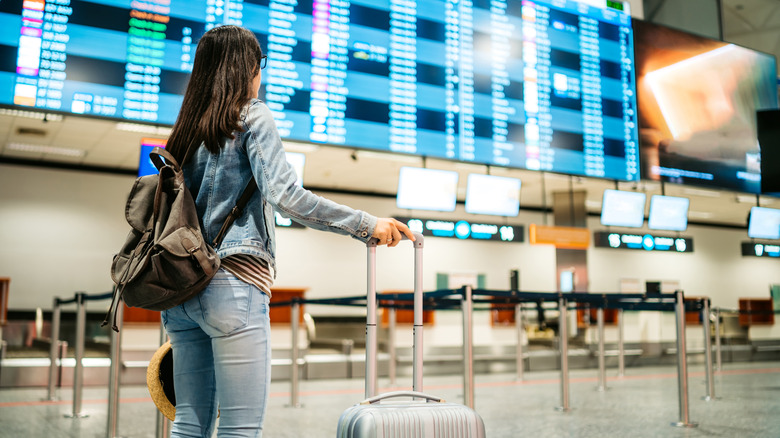 Young Asian female tourist checking the arrival departure board at airport in Budapest.
