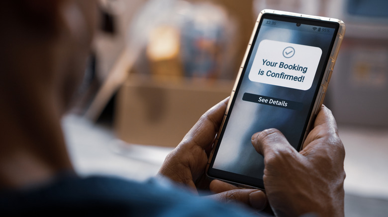 A man booking tickets on a cell phone.