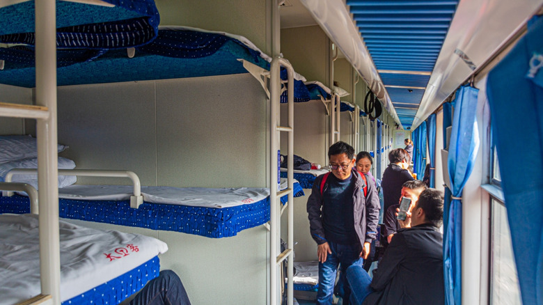 People in the hallway of a Chinese sleeper train.