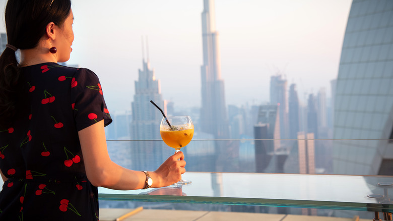 Woman having a drink while looking on the Dubai skyline