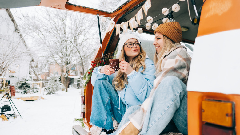 Two women sitting in a camper van in winter