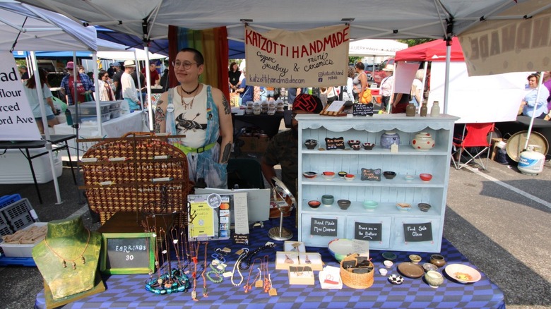A smiling vendor sells ceramics and jewelry at the 32nd Street Farmers Market in Baltimore.