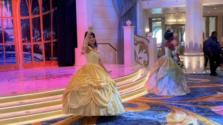 Princesses Belle, Tiana, and Rapunzel in the lobby of the Disney Wish cruise ship